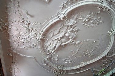 <p>Het weelderige stucplafond heeft een opschrift met het jaartal 1750. Het plafond wordt gedomineerd door een grote middenfiguratie, met een slapende vrouw,  twee putti met een lint en twee appel- of sinaasapppelbomen. </p>
